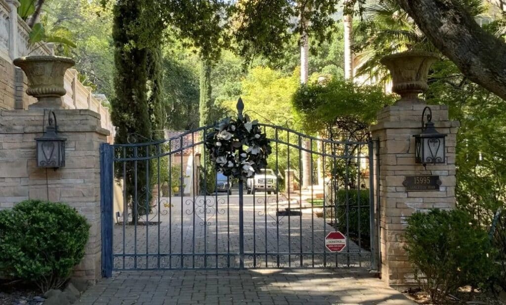 Elegant wrought iron entry gate framed by lush greenery and custom stone columns in Monte Sereno, CA. Ideal for enhancing curb appeal and security with timeless landscape design.