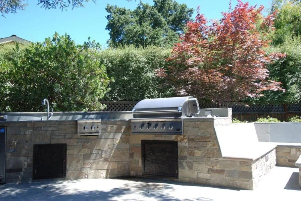 A modern outdoor BBQ area with a built-in grill and stone veneer, designed for durability and style in Los Altos. Ideal for outdoor cooking and entertaining in the Bay Area.
