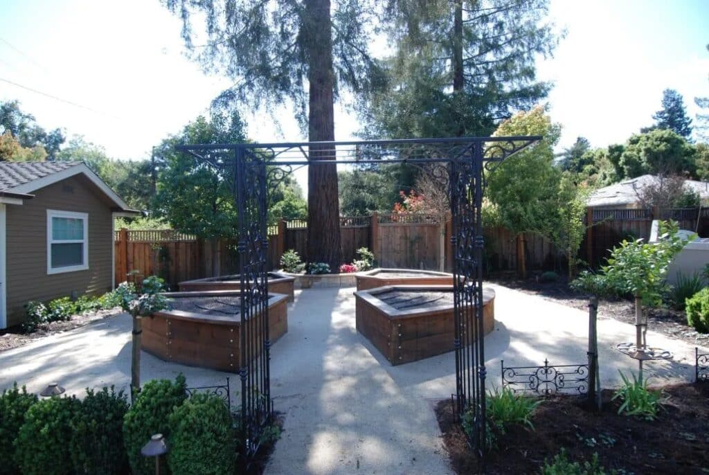 Custom-built wooden planters with decorative iron trellises in a serene backyard setting. A sophisticated garden solution for homeowners in Los Altos Hills and surrounding Bay Area communities.