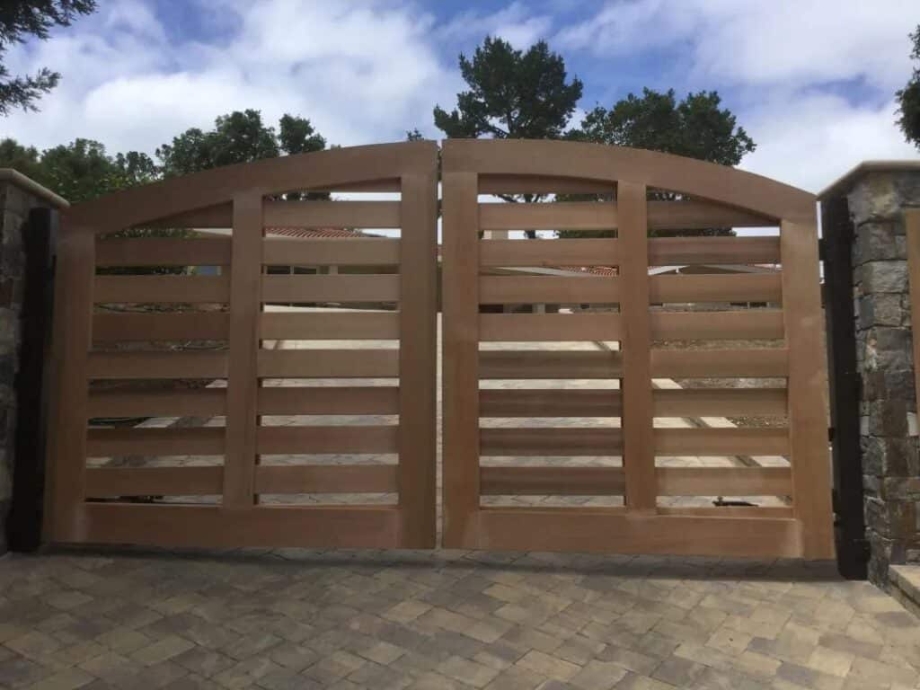 Beautifully crafted wood driveway gate with horizontal slats and stone pillars, adding curb appeal and security to a Los Altos Hills property.