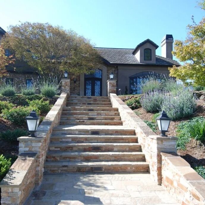 Grand stone staircase with built-in lighting and lush greenery in Saratoga, CA. Ideal for enhancing curb appeal and showcasing sophisticated hardscaping design.